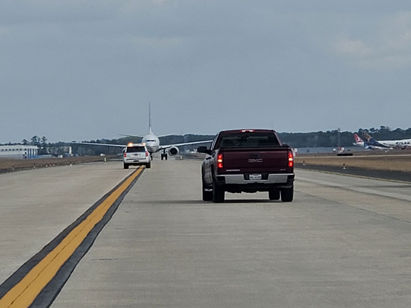 Escort vehicle leading an aircraft along an airfield taxiway at the Houston Airport System